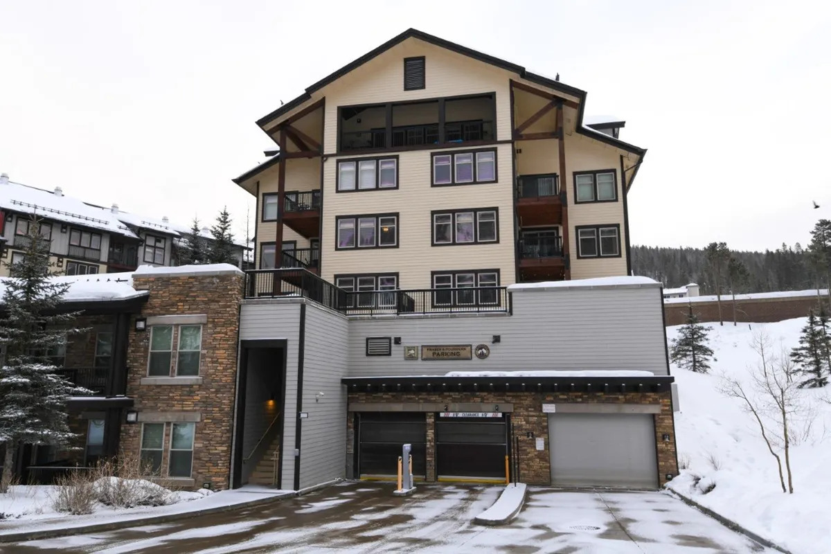 This image showcases a large multi-story building with a stone façade, surrounded by snow-covered ground and balconies overlooking the winter landscape. The scene evokes a sense of luxury and proximity to winter activities, perfectly capturing the ski-in/ski-out experience at Winter Park Resort.