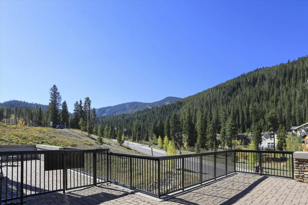 This image showcases a scenic patio with a railing overlooking a breathtaking mountain range and dense forest, evoking the tranquility of the natural surroundings. The setting suggests relaxation and outdoor enjoyment, with ample opportunity to take in sunsets or stargaze, perfectly complementing the immersion in panoramic mountain views mentioned in the section.