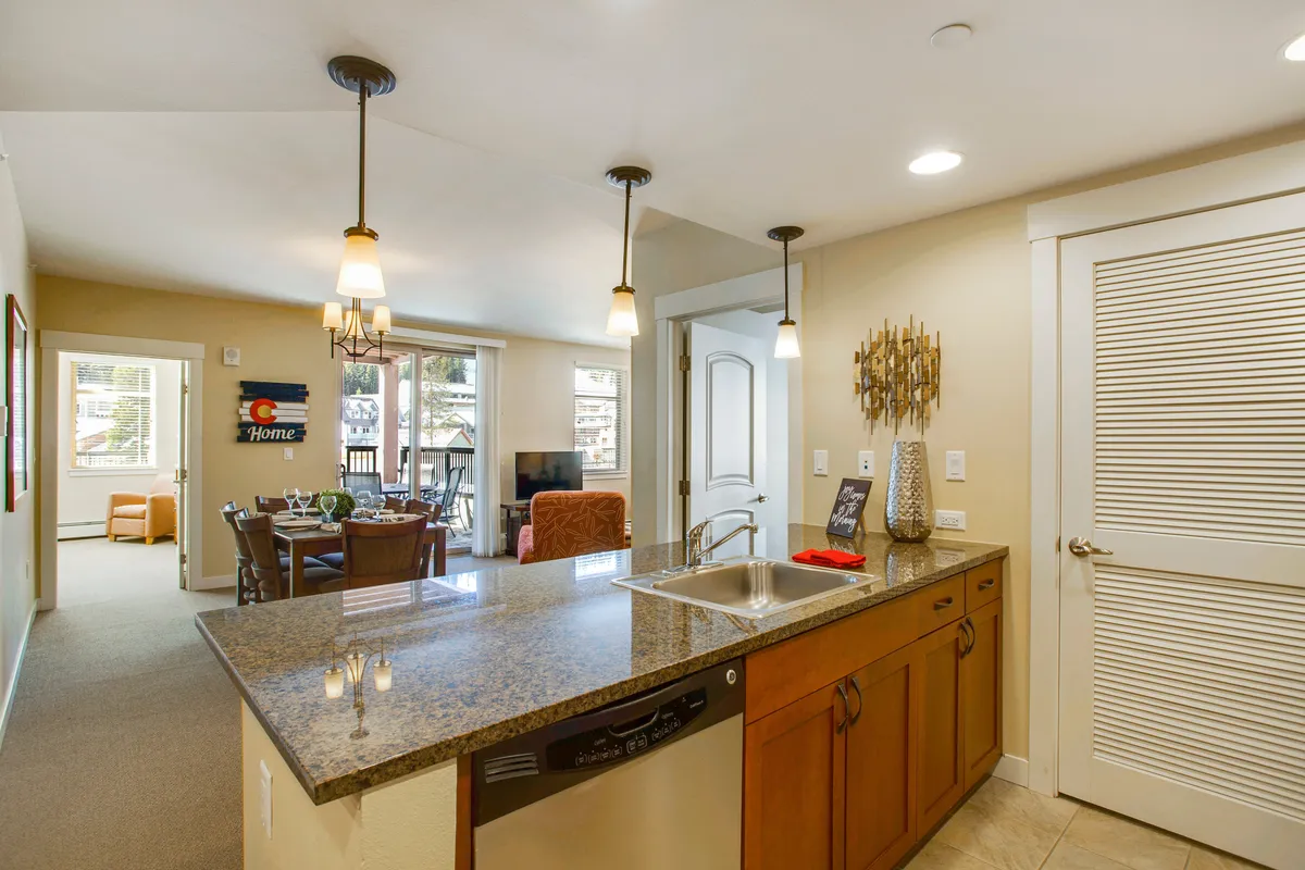 A spacious, cohesive interior shot capturing the kitchen island, dining area, and living room seating. The layout encourages socializing, with plenty of seating for family game nights or shared meals. The soft lighting and decor create a cozy, welcoming mood.