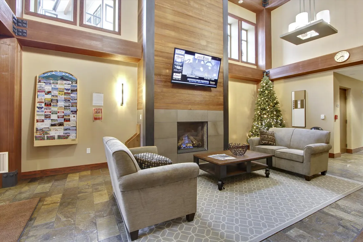 A cozy common area with a fireplace, Christmas tree, seating, a TV, and an information board. The space is decorated for the holidays, and offers a warm, communal atmosphere ideal for relaxing or socializing after a day of resort activities.